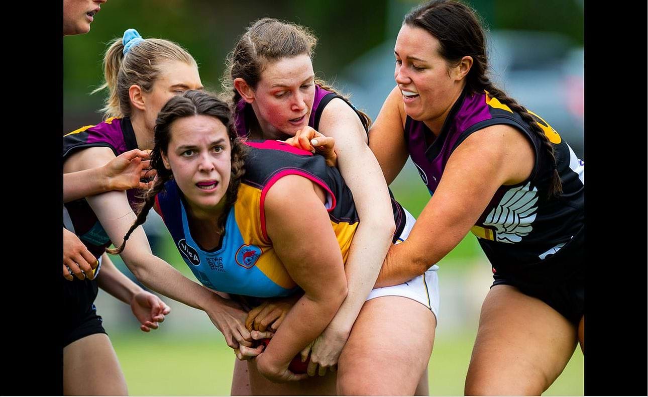 Lauren Oliver in the centre leads the tackle of her Old Mentonians opponent, helped by Ellen Russell at left and Zoe Preston at right