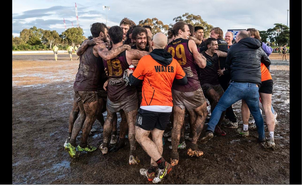 Soon to be muddied coach Daniel Ward joins his players in the huddle