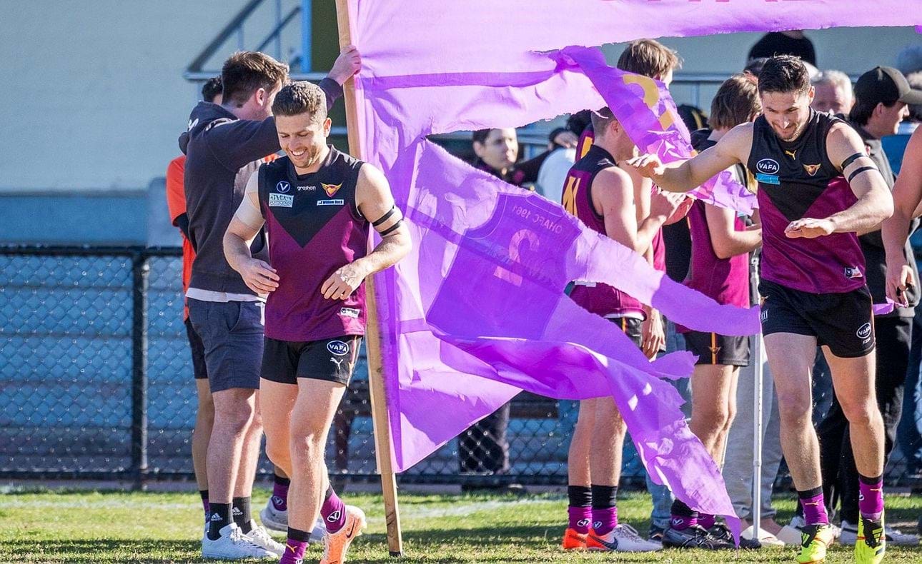 James Paul breaks through the banner celebrating his 200th game, closely followed by captain Brede Seccull playing his 50th