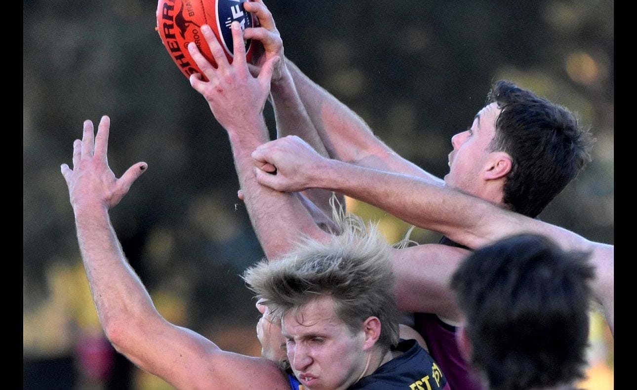 Charlie Harrop winces in the foreground as Lachie Vaughan stretches for a mark
