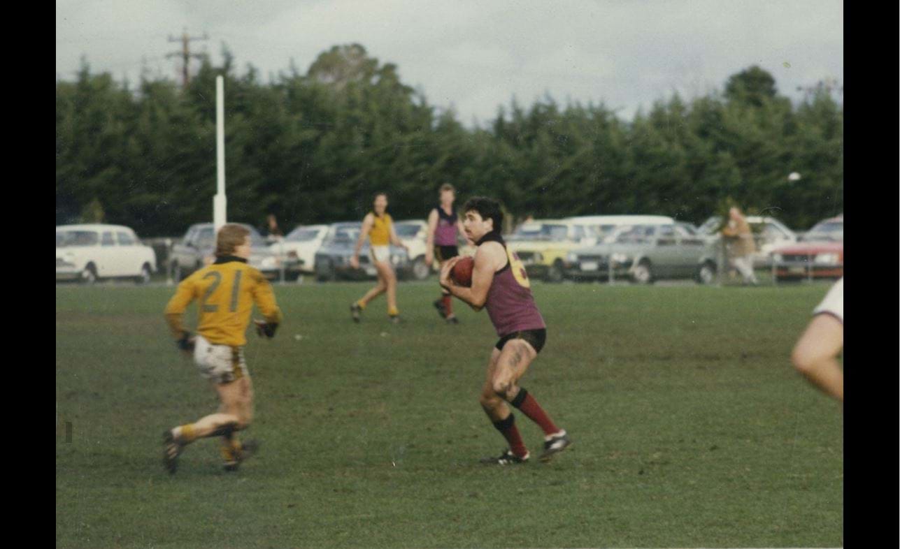 John Kingsley marks against Old Trinity at McKinnon in 1986 but looks full of worry. He might be trying to find a way of swinging onto that favourite left foot. Some of his number 66 is visible, as is his good mate Jeff Robertson in the background.