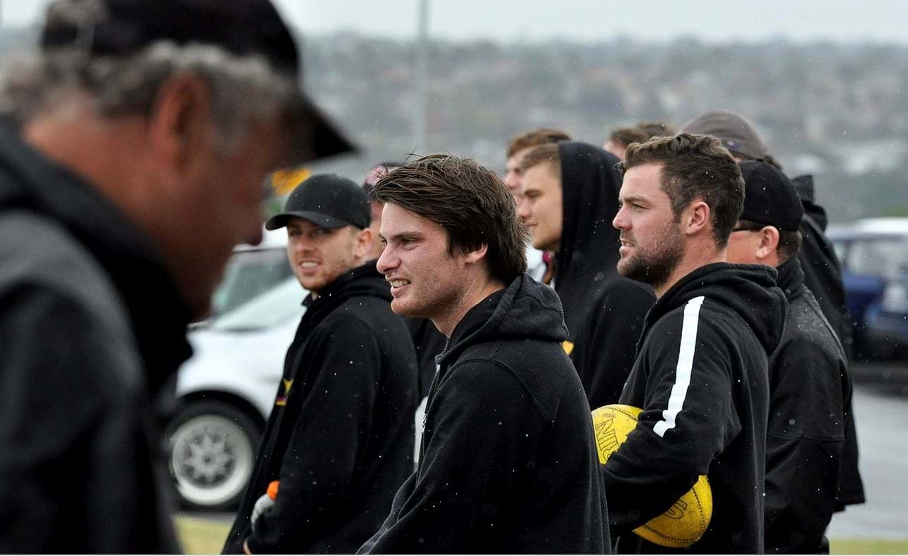 Nick Gooda (centre) along with other members of the senior team watch the Reserves take on Penleigh and Essendon Grammar (PEGS) on a wet day out at Keilor for Round 3