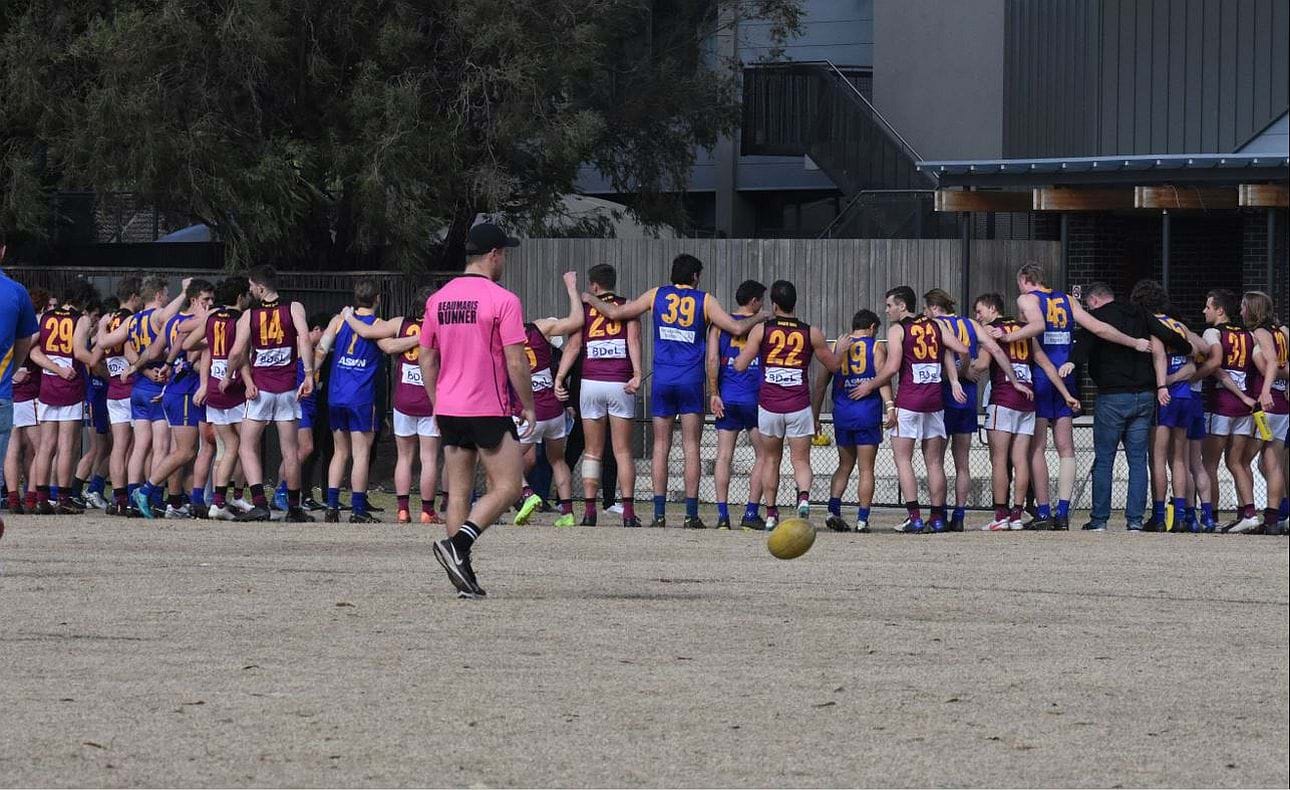 The teams lock arms before the game